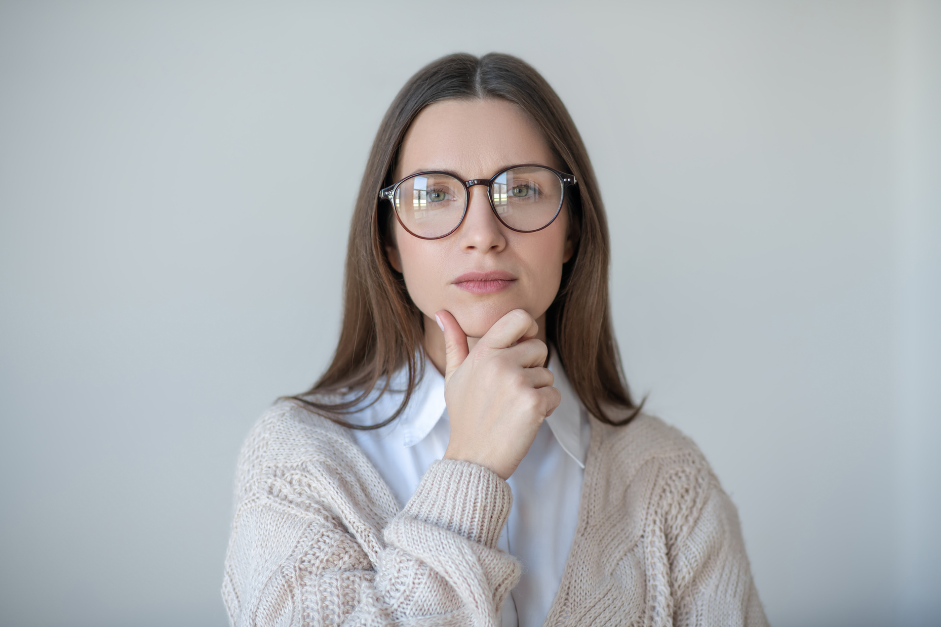 Headshot of long-haired woman in eyeglasses looking thoughtful